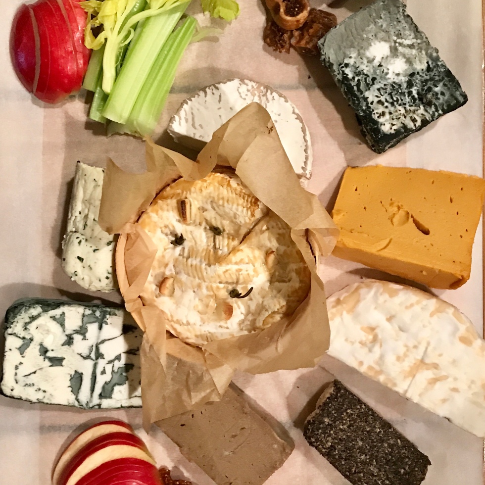 9 Vegan cheeses laid on a board with fruit and crackers surrounding them