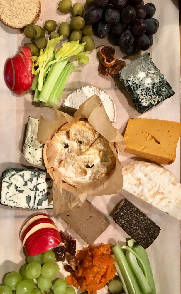 9 Vegan cheeses laid on a board with fruit and crackers surrounding them