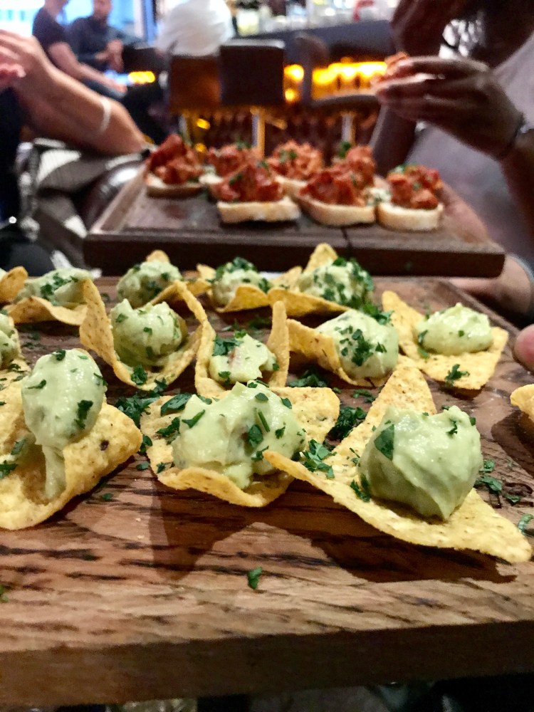 A board of mini tomato and toast on the far side and nachos with dip closer to the picture